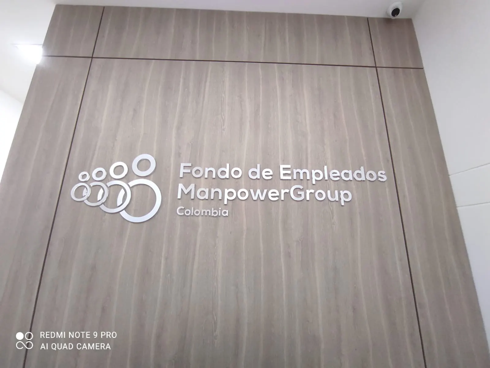 Letras corpóreas con logo sobre pared de madera en una oficina
