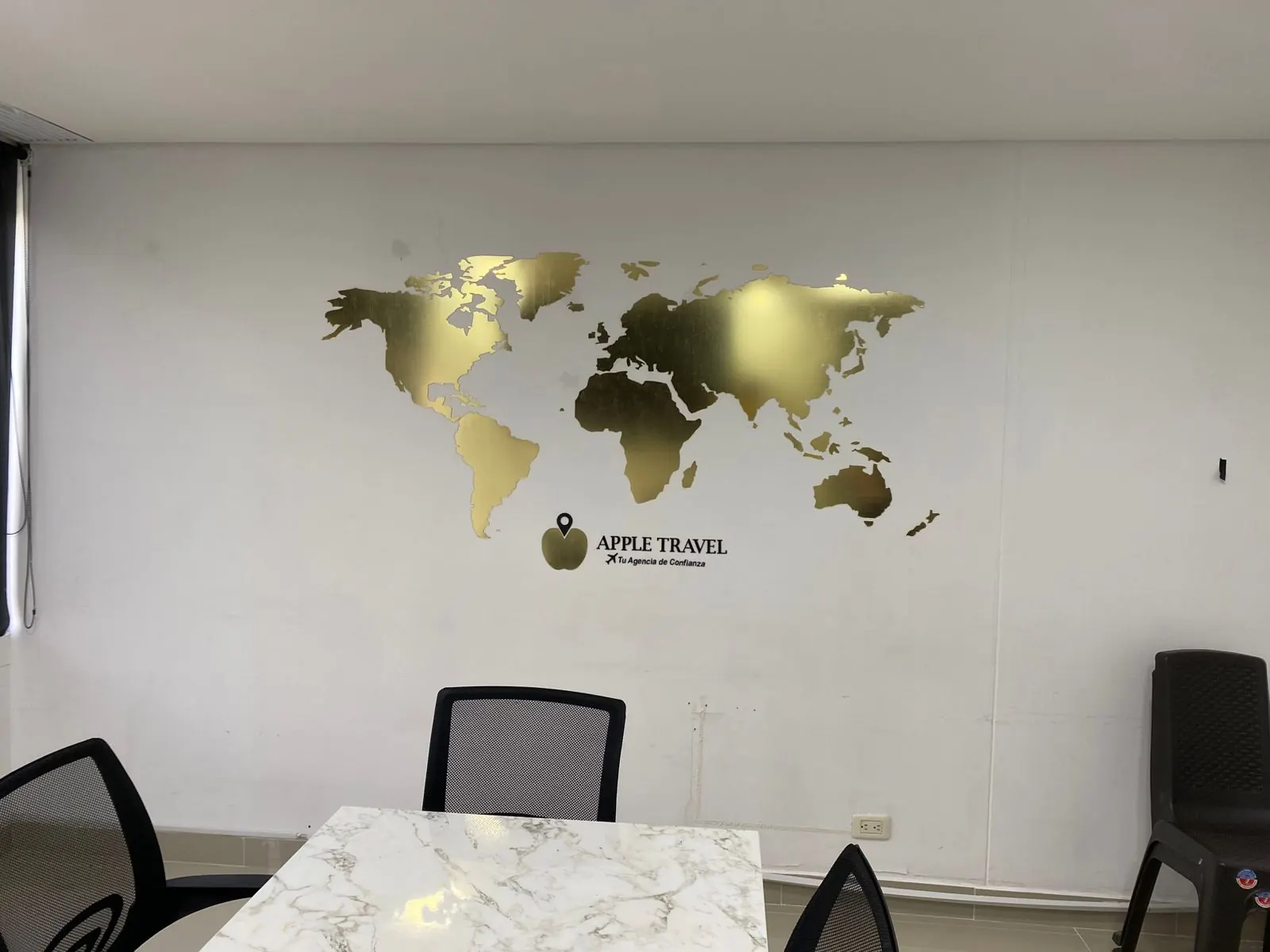 Mapa mundi en acrílico dorado con logo en la pared de una oficina